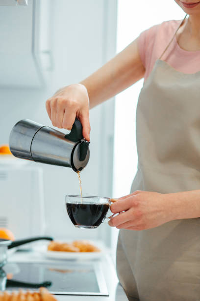 istock Young lady wearing apron making coffee at home 1307541942