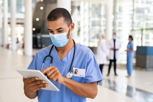 병원에서 디지털 태블릿을 사용하여 혼합 인종 간호사 - nurse doctor scrubs male 뉴스 사진 이미지