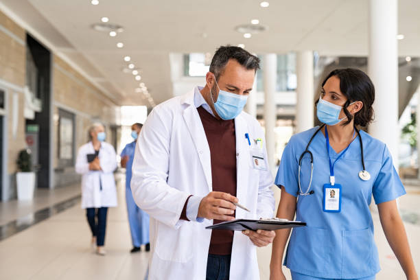 medico maturo e infermiere discutono del caso del paziente - doctors and nurses foto e immagini stock