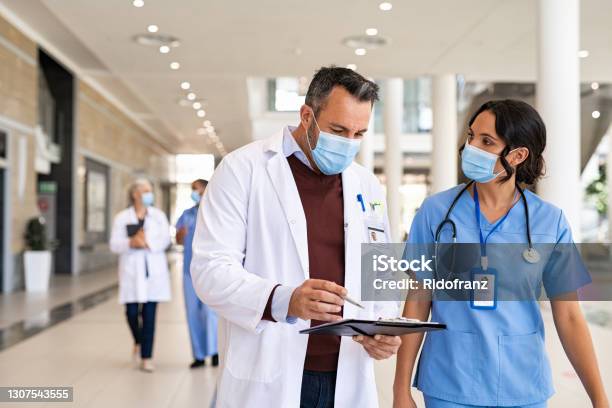 Mature Doctor And Nurse Discussing Patient Case Stock Photo - Download Image Now - Doctor, Healthcare And Medicine, Nurse