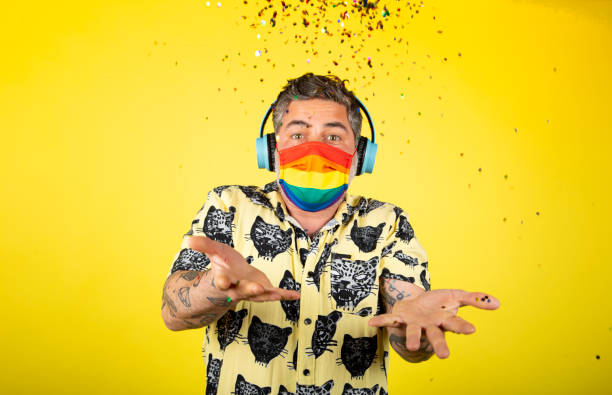 loco con máscara celebrando el día del orgullo gay sobre un fondo amarillo - gay pride flag audio fotografías e imágenes de stock