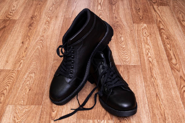istock Black leather mens boots on wooden floor 1307548614