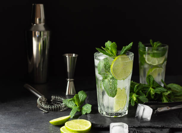 istock Refreshing summer mojito cocktail with ice cubes, fresh mint and lime on black. 1307548967