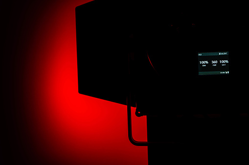 One LED stage lights with protective shutters on red background, copy space. The scene is situated in controlled studio environment in front black and red background. The photo is shot with Sony A7III camera.