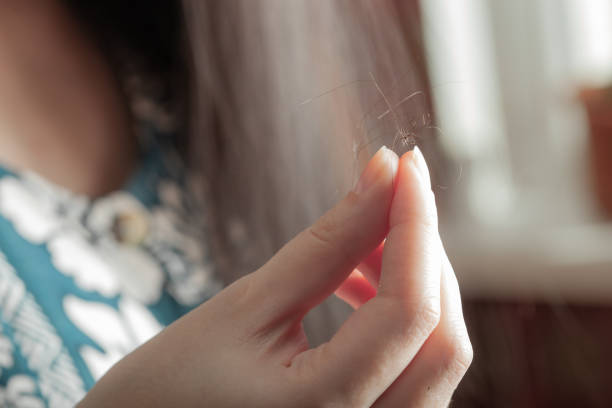 Girl holds a strand of hair near the window. hair loss concept Girl holds a strand of hair front view. hair loss concept hair strands stock pictures, royalty-free photos & images