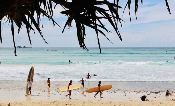 surfisti con tavole da surf che camminano sulla sabbia nella famosa spiaggia di wategos - surfing new south wales beach australia foto e immagini stock