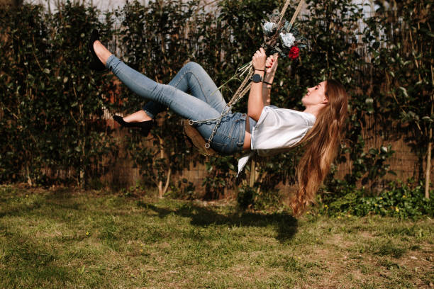 Young woman on a swing holding a flower bouquet