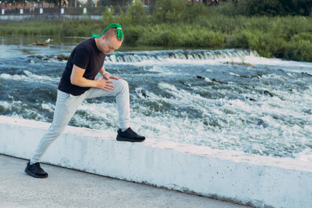 istock A man with an interesting mohawk hairstyle from braided braids doing a stretching exercise on the bank of a stormy river 1307552500