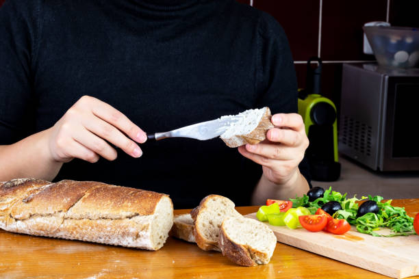 istock Woman spread basil and parsley cream over baguette. Selective focus. 1307553622