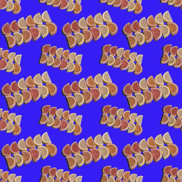 Decorative seamless pattern of fruit marmalade in the form of slices of citrus fruit laid out on a blue background. Jelly sweet candies. Top view.