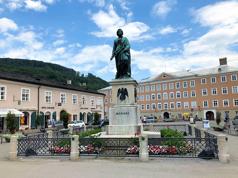 Statue of the famous composer Wolfgang Amadeus Mozart on a little square with flowers surrounded with buildings on a sunny day in the city of Salzburg in Austria June 10,2018