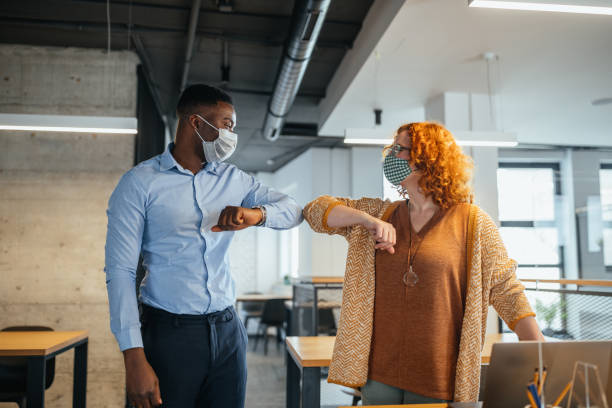istock Diverse colleagues in facial masks bumping elbow 1307555533
