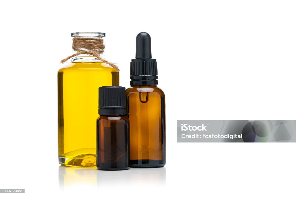 Aromarherapy and health care: essential oil and massage oil isolated bottles on white background Essential oil and massage oil bottles isolated on white background. The composition is at the left of an horizontal frame leaving useful copy space for text and/or logo at the right. High resolution 42Mp studio digital capture taken with Sony A7rII and Sony FE 90mm f2.8 macro G OSS lens Essential Oil Stock Photo