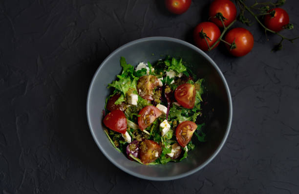 istock Fresh salad with tomatoes, arugula and cheese cubes, black plate 1307563839