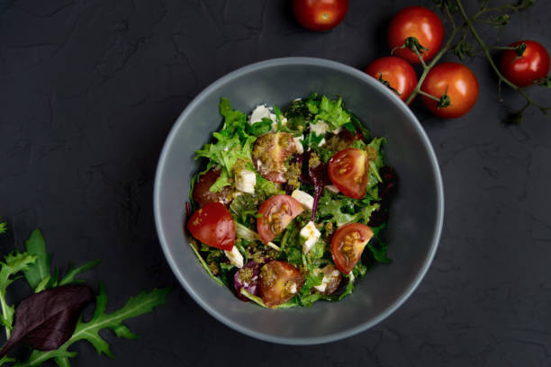 istock Fresh salad with tomatoes, arugula and cheese cubes, black plate 1307563871