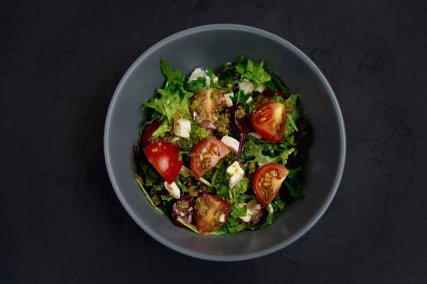 istock Fresh salad with tomatoes, arugula and cheese cubes, black plate 1307563968