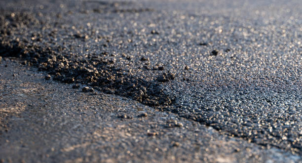 Freshly laid black bitumen asphalt with a high edge to the gravel showing the structure. Laying a new asphalt on the roads. Construction of the road. stock photo