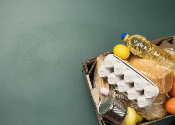 caixa de papelão com vários produtos, frutas, massas, óleo de girassol em uma garrafa plástica e preservação. conceito de doação - oat packaging oatmeal box - fotografias e filmes do acervo