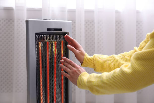 Woman warming hands near heater indoors, closeup Woman warming hands near heater indoors, closeup electric heater photos stock pictures, royalty-free photos & images