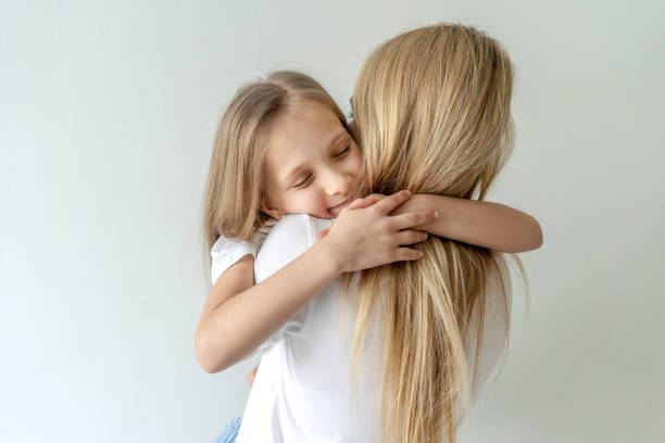 istock Mom and daughter hugging on light background. 1307566176