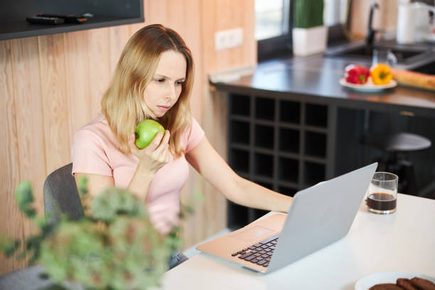 istock Charming woman with apple using modern laptop at home 1307568024