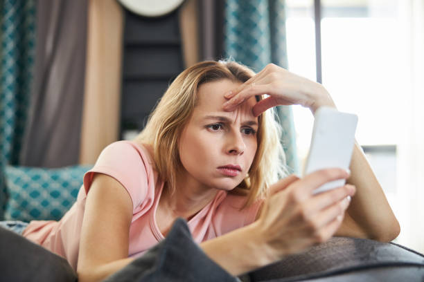 istock Confused pretty woman reading message on mobile phone 1307568099