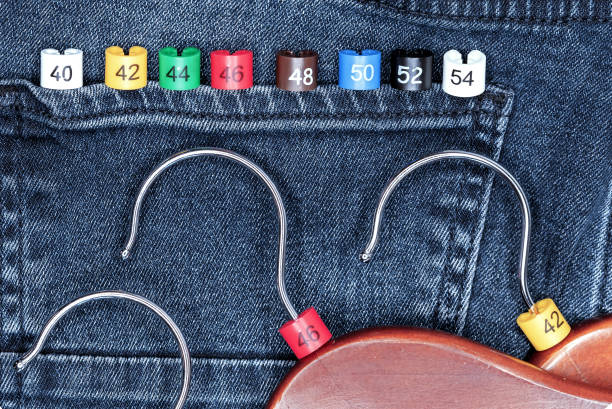 istock Clothes hangers with multicolored plastic size labels on a denim backdrop. 1307569483