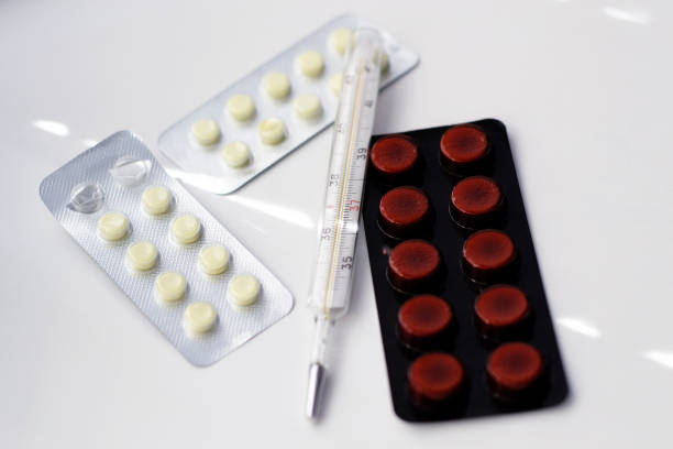 istock Tablets and a thermometer on a white table. Treatment of viruses. 1307571456