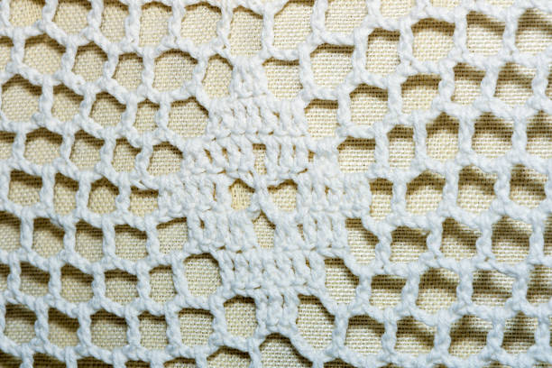 Fragment of knitted lace white textile tablecloth on the table close-up
