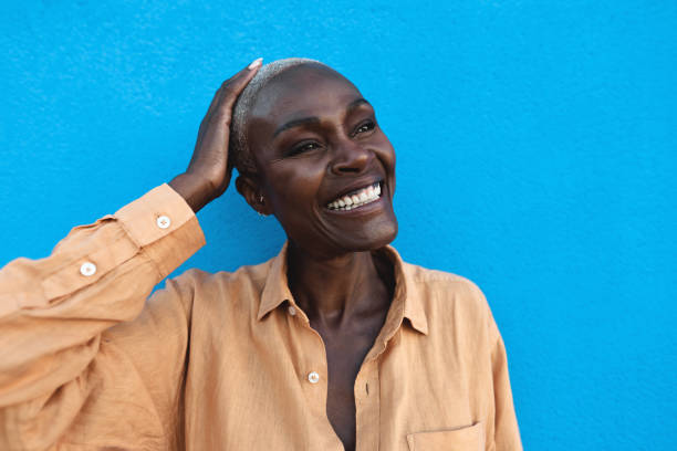 lycklig afrikansk kvinna porträtt - afro senior kvinna har kul medan du står på blå bakgrund - mature women model bildbanksfoton och bilder