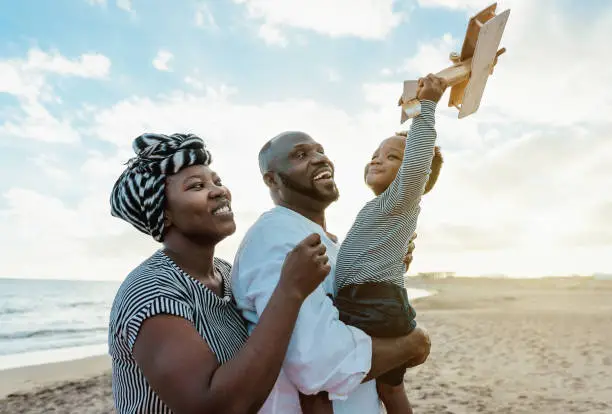 Photo of Happy African family having fun on the beach during summer vacation - Parents love and unity concept