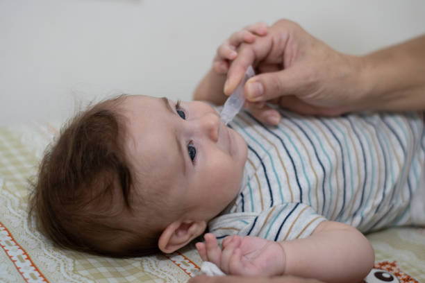 Baby taking droplet vaccine to prevent rotavirus stock photo