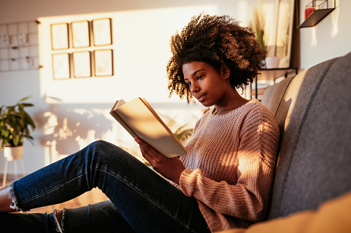 Young African American woman at home, dressed in casual sweater and working or studying.