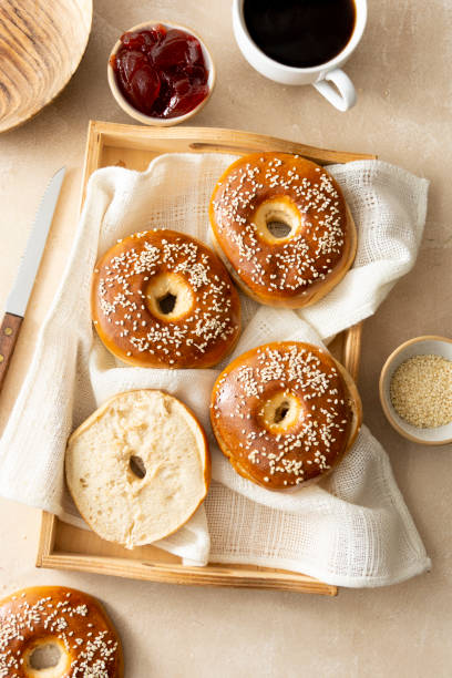 pains de pâtisserie de bagels pour le petit déjeuner, avec la tasse de café et la confiture de fruit. vue supérieure, fond lumineux, lumière naturelle. - bagel coffee morning breakfast photos et images de collection