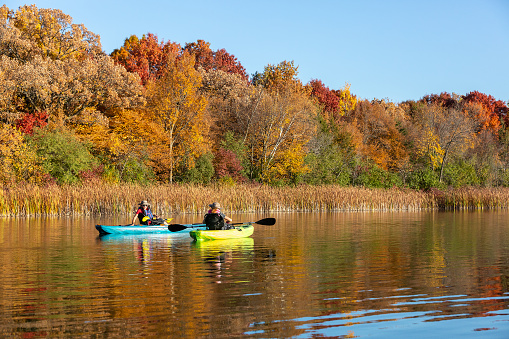 Two young girls (sisters) kayaking on a lake in autumn.