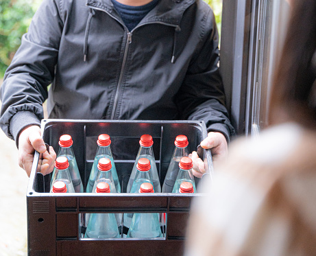 close up of a delivery man holding a box with water bottles