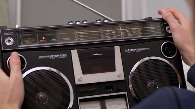 Male Holds Vintage Audio Tape Recorder in Hands with Rotating Audio Cassette