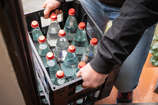close up of a delivery man holding a box with water bottles