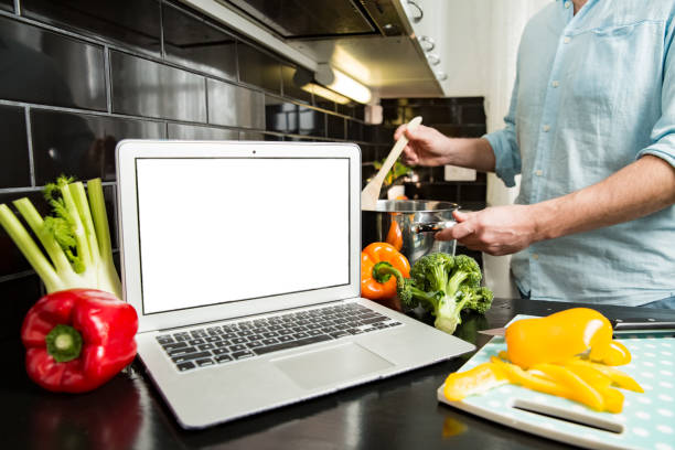 istock Man using laptop and cooking in kitchen at home. 1307587020