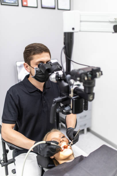 istock Male dentist examining patient looking on the teeth with professional microscope at surgery dental office 1307588562