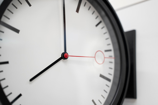 Round black and white clock with both the hour hand and minute hand almost pointing to 12 o'clock. Illustration of the concept of due date, deadline, countdown and doomsday