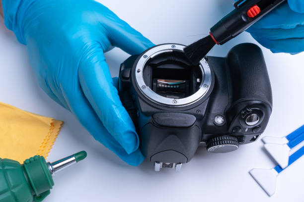The technician cleans the sensor of the DSLR camera with a brush