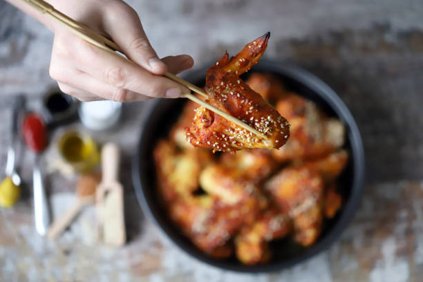 istock Male hand with chopsticks keeps spicy chicken wings. 1307591680