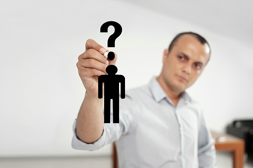 Businessman drawing a man icon with question mark on virtual screen.