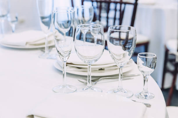 istock Fancy table set for dinner with napkin glasses in restaurant, luxury interior background. Wedding elegant banquet decoration and items for food arranged by catering service on white tablecloth table 1307594328