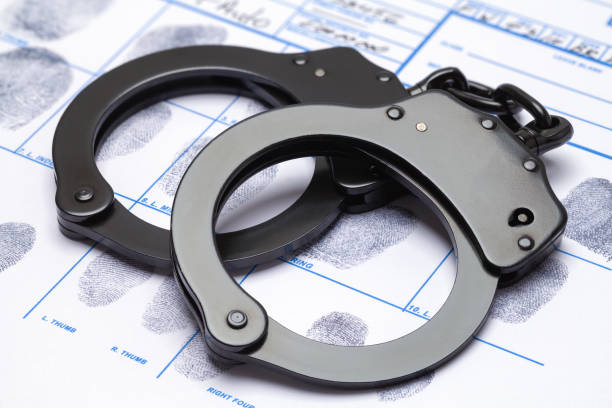 Handcuffs and Fingerprints Black Metal Handcuffs and Fingerpints on Chart. arrest photos stock pictures, royalty-free photos & images
