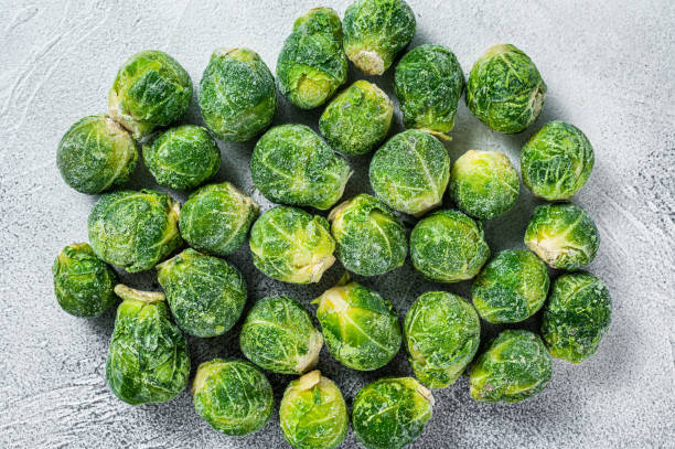 istock Frozen Brussels sprouts green cabbage on kitchen table. White background. Top view 1307595152