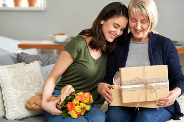 madre e hija desempacan un regalo juntos - día de la madre fotografías e imágenes de stock