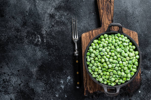 istock Fresh Frozen green peas in a pan. Black background. Top view. Copy space 1307597154
