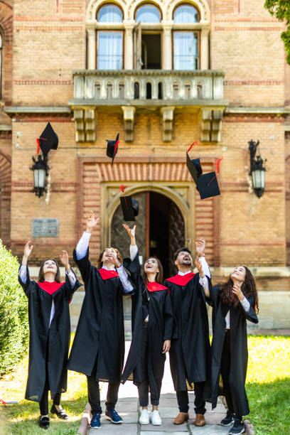 istock Graduating students throwing caps in the air at University ceremony 1307597756